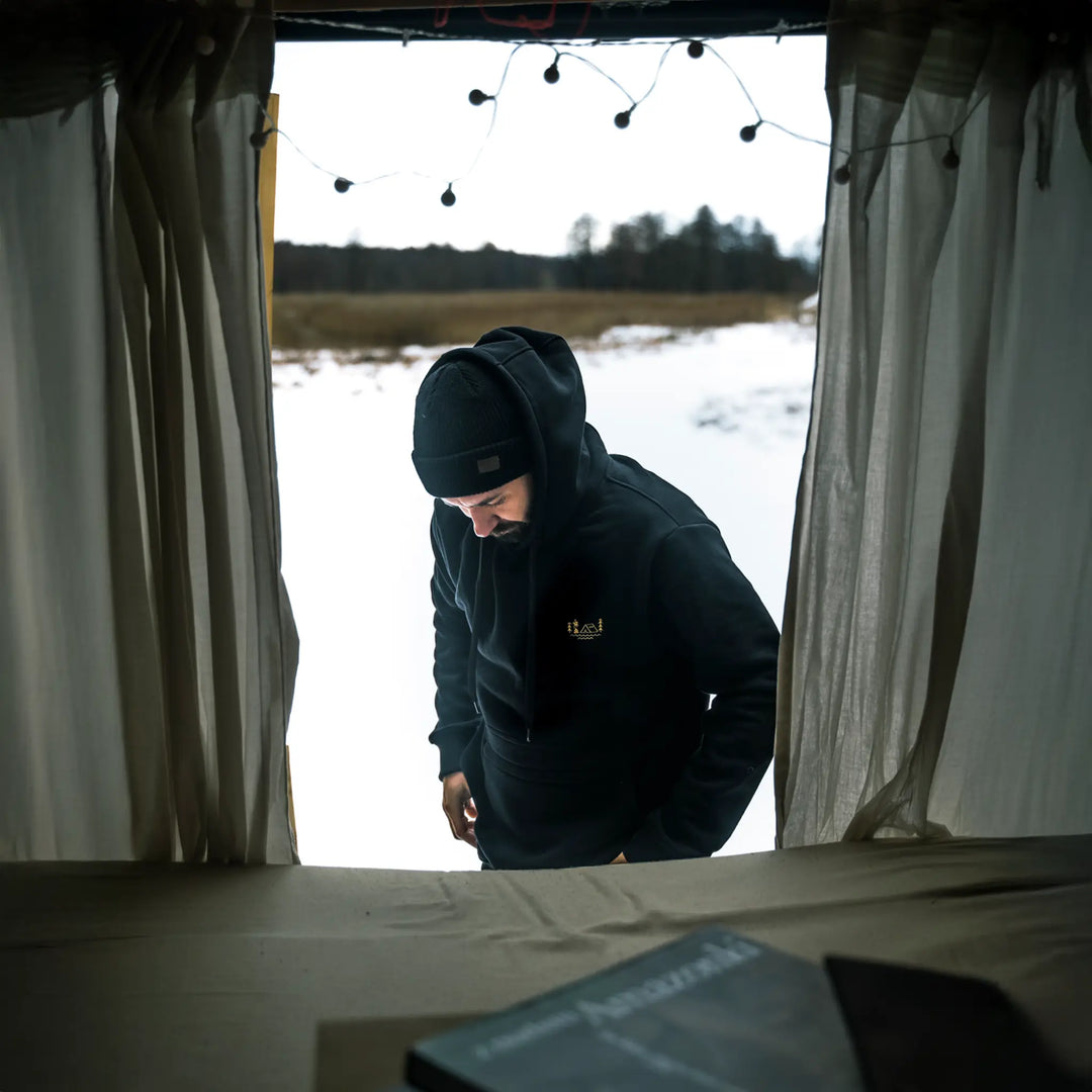 Czarna bluza Wild Fish Stories El Clasico noszona w kamperze, zimowy outdoorowy styl życia podczas postoju w naturze