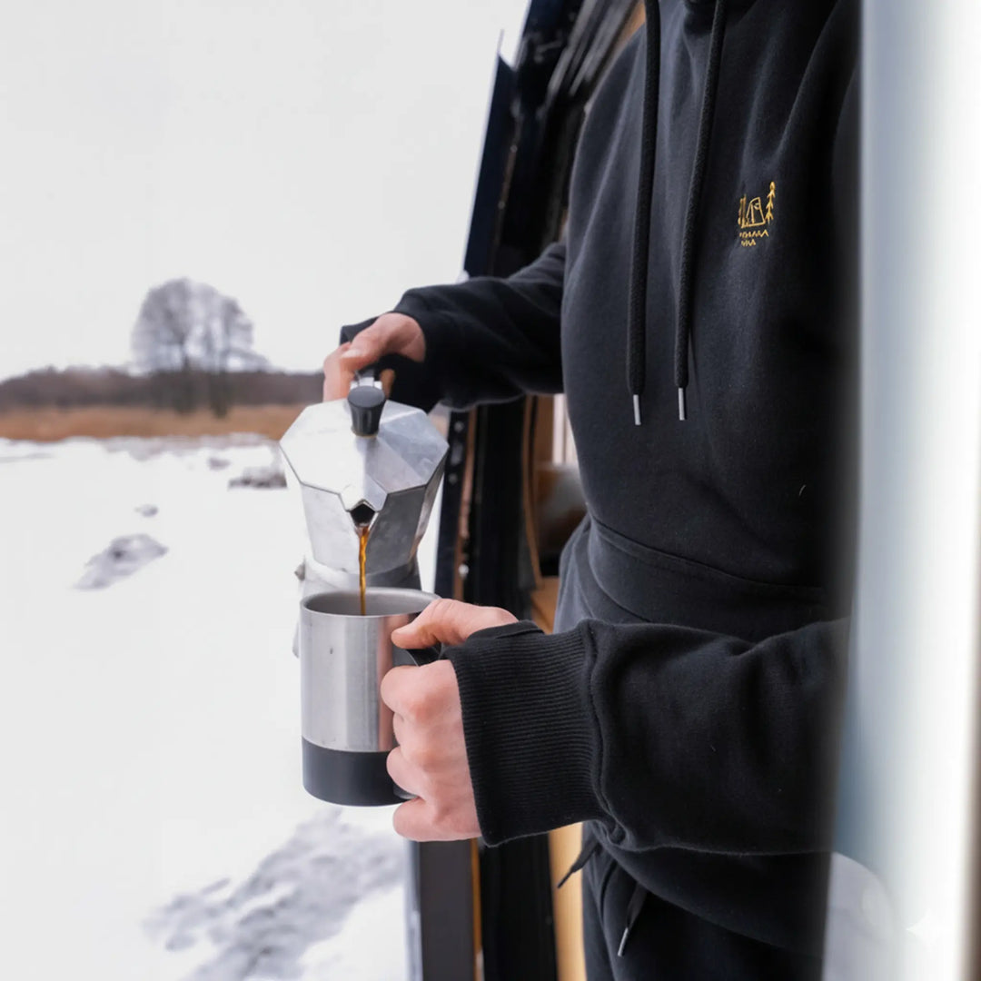 Czarna bluza wędkarska Wild Fish Stories El Clasico noszona w plenerze, parzenie kawy w kawiarce podczas zimowego outdoorowego wypoczynku
