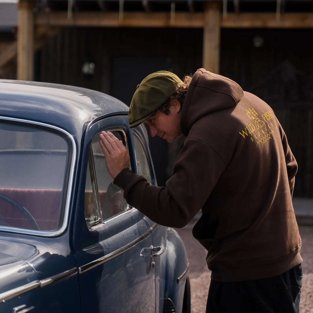 Bluza Wild Fish Stories z logo na plecach noszona w plenerze, outdoorowy styl życia przy klasycznym samochodzie