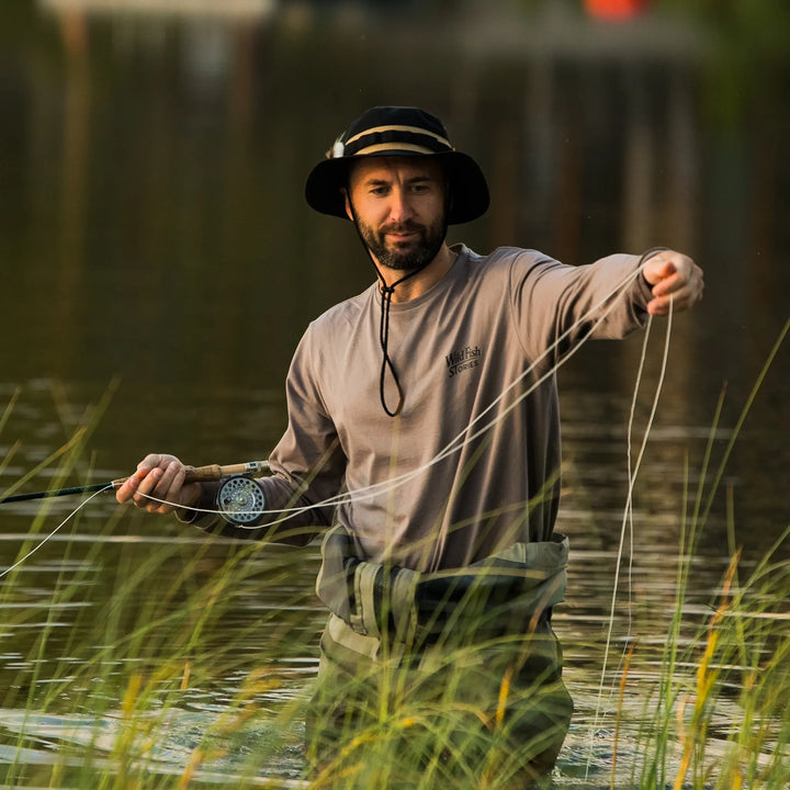 Longsleeve Wild Fish Stories Camper Chill podczas łowienia muchowego w wodzie, mężczyzna w kapeluszu, outdoorowy longsleeve z logo na piersi, styl kamper i slow fishing